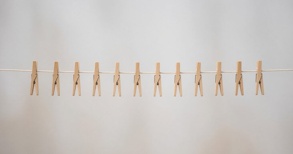 Twelve wooden clothespins in a row on a plain cord.